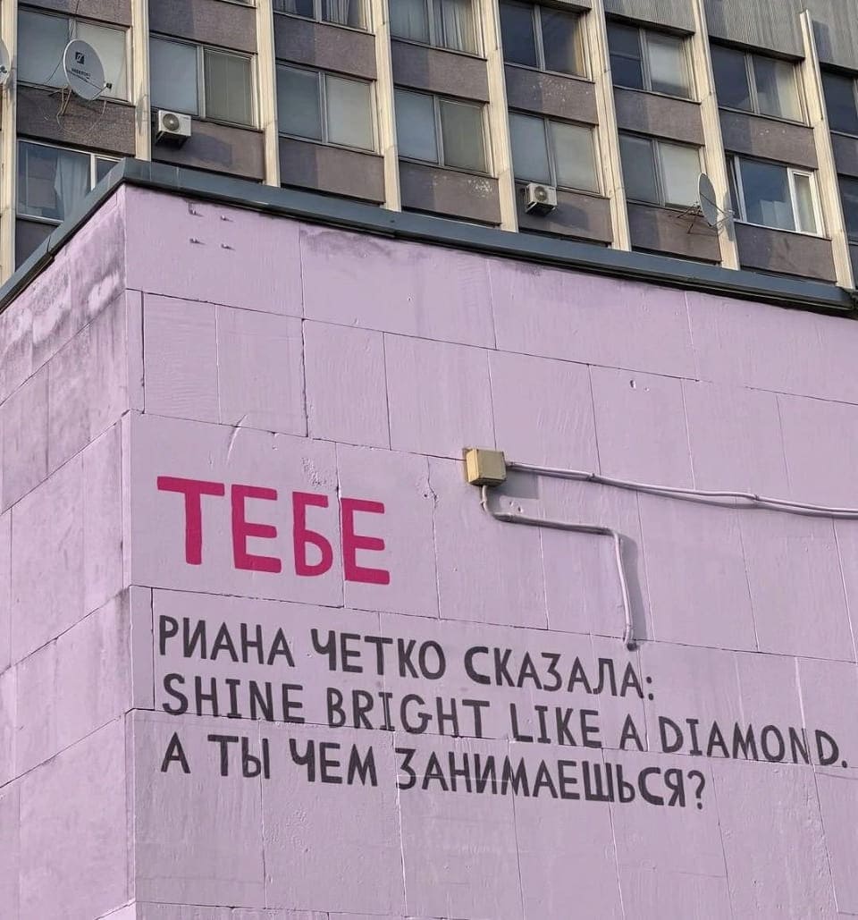 ТЕБЕ РИАНА Чётко СКАЗАЛА: SHINE BRIGHT LIKE A DIAMOND. А ТЫ ЧЕМ ЗАНИМАЕШЬСЯ?

Это городской билборд на фасаде здания. На светло-фиолетовой панели крупными красными буквами написано «Тэбе», под которым чёрным шрифтом фраза «Риана чётко сказала: SHINE BRIGHT LIKE A DIAMOND. А ты чем занимаешься?». Окна здания сверху, провод и выключатель на стене.
