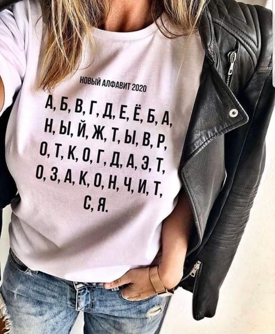 НОВЫЙ АЛФАВИТ 2020 А, Б, В, Г, Д, Е, Ё, Б, А, Н, Ы, Й, Ж, Т, Ы, В, Р, О, Т, К, О, Г, Д, А, Э, Т, О, З, А, К, О, Н, Ч, И, Т, C, Я. <br /><br /> Фотография женщины в белой футболке и чёрной кожаной куртке. На футболке написано «Новый алфавит 2020», а ниже — список букв русского алфавита, расположенных в хаотичном порядке. Женщина одета в джинсы и держит руки в карманах. Фон неочевиден, но акцент сделан на футболке с необычной надписью.