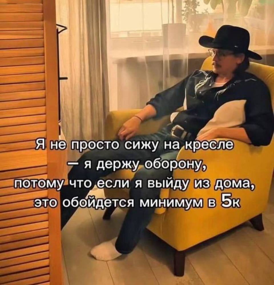 — Я не просто сижу на кресле — я держу оборону, потому что если я выйду из дома, это обойдётся минимум в 5к. <br /><br /> Описание картинки: <br /> Мужчина сидит на диване в уютной комнате, одет в черную рубашку и шляпу. | Продавец | Покупатель
